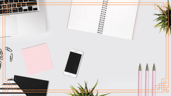 Biurko z rozłożonymi rzeczami - laptop, komórka, długopisy, notatnik, spinacze.